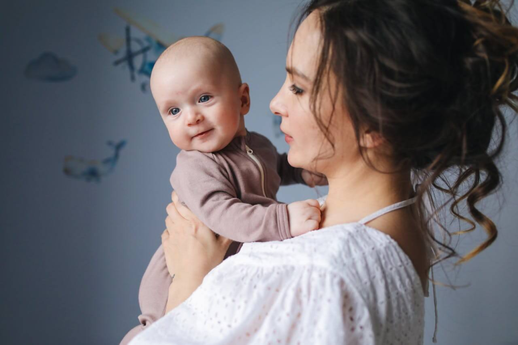 First-time mom holding her baby while looking worried, representing postpartum anxiety.