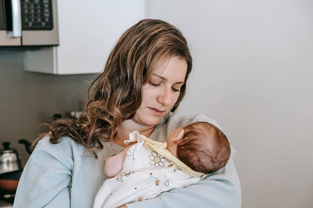 First-time mother holding her newborn while experiencing racing thoughts from postpartum anxiety.