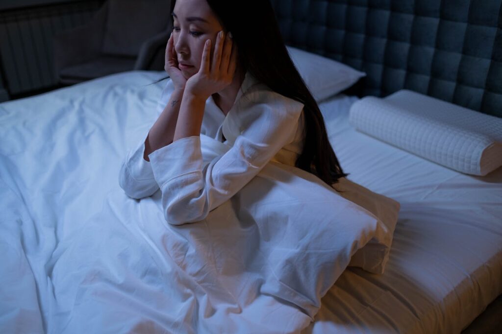 Sleep deprived new mom sitting in bed exhausted but alert at night due to postpartum anxiety