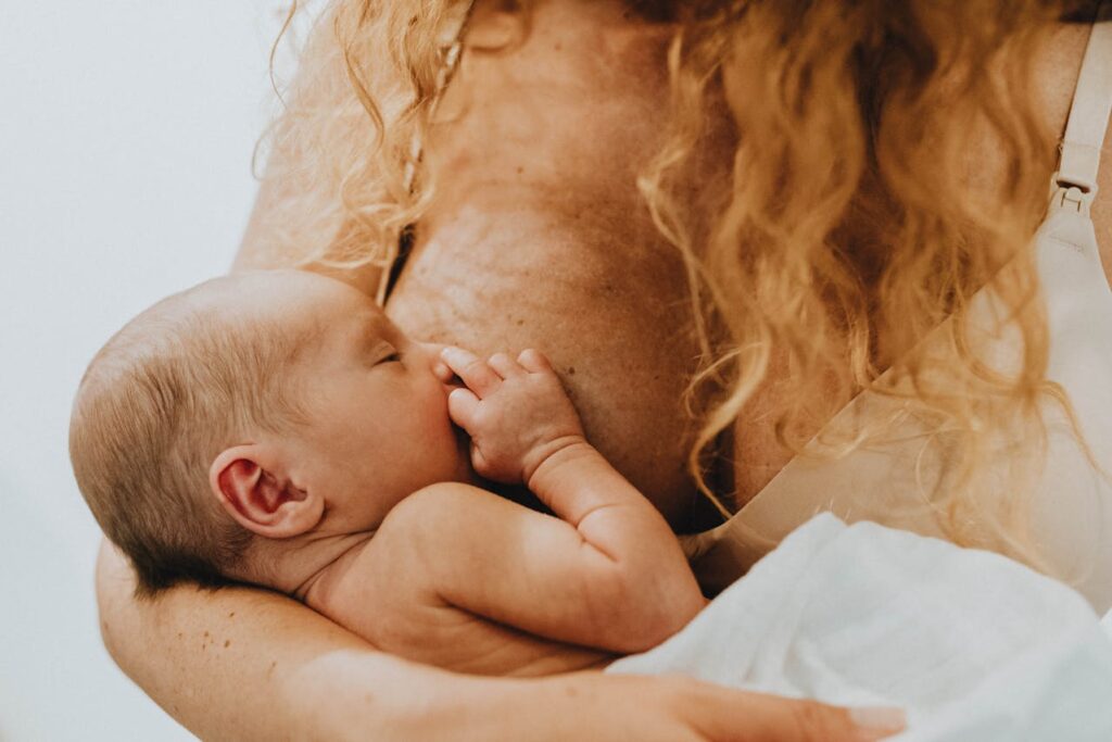 New mom breastfeeding her baby while feeling anxious and overstimulated.