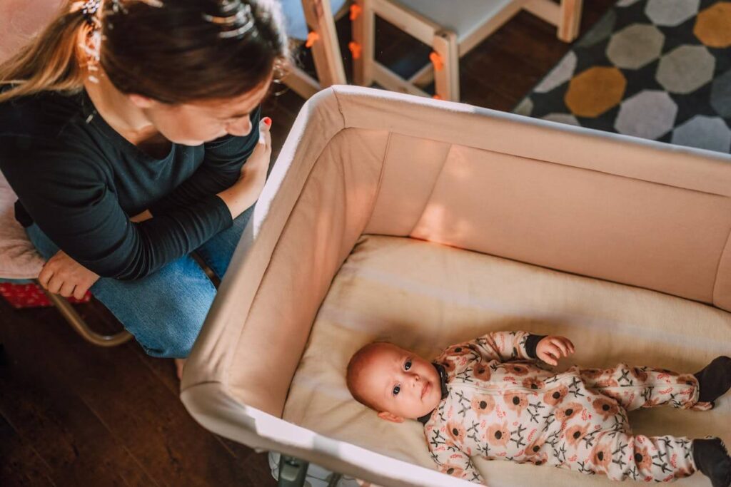First-time mom watching her baby in the crib while struggling with postpartum anxiety and fear of something bad happening to her baby.