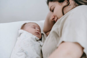 Tired first-time mom lying awake at night watching her baby sleep due to postpartum anxiety
